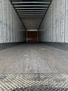 Utility van trailer interior showing empty cargo area with metal sidewalls and a diamond plate threshold.