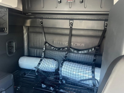 Freightliner Cascadia 126 sleeper interior showing cargo area with rolled mat and netting straps.