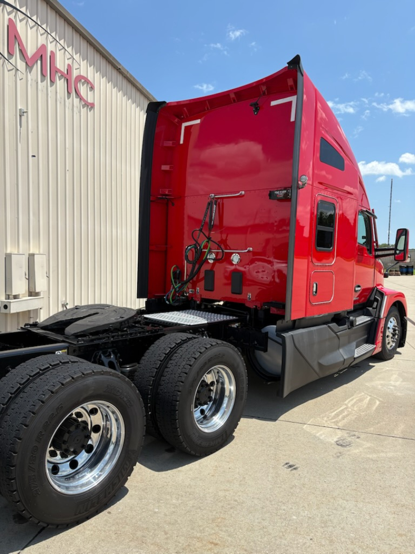 Kenworth T680 truck cab rear and chassis with red exterior and dual rear axles, view from side rear showing back of cab and wheel area.