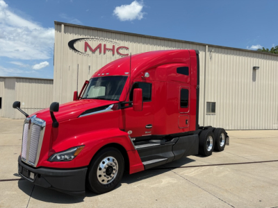 Kenworth T680 red tractor-trailer from the side in a dealership lot showing front grille and cab details.