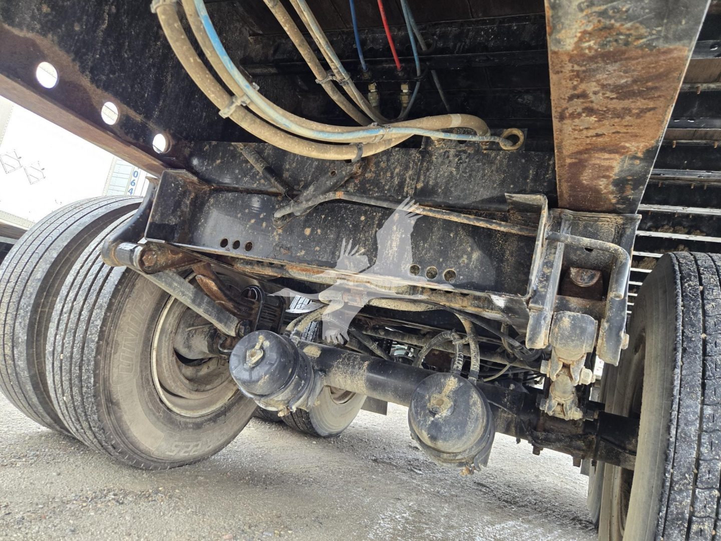 Trailer undercarriage showing steering and suspension components, dual axles, leaf springs, and hydraulic hoses on a 2018 Dorsey steel flatbed trailer.