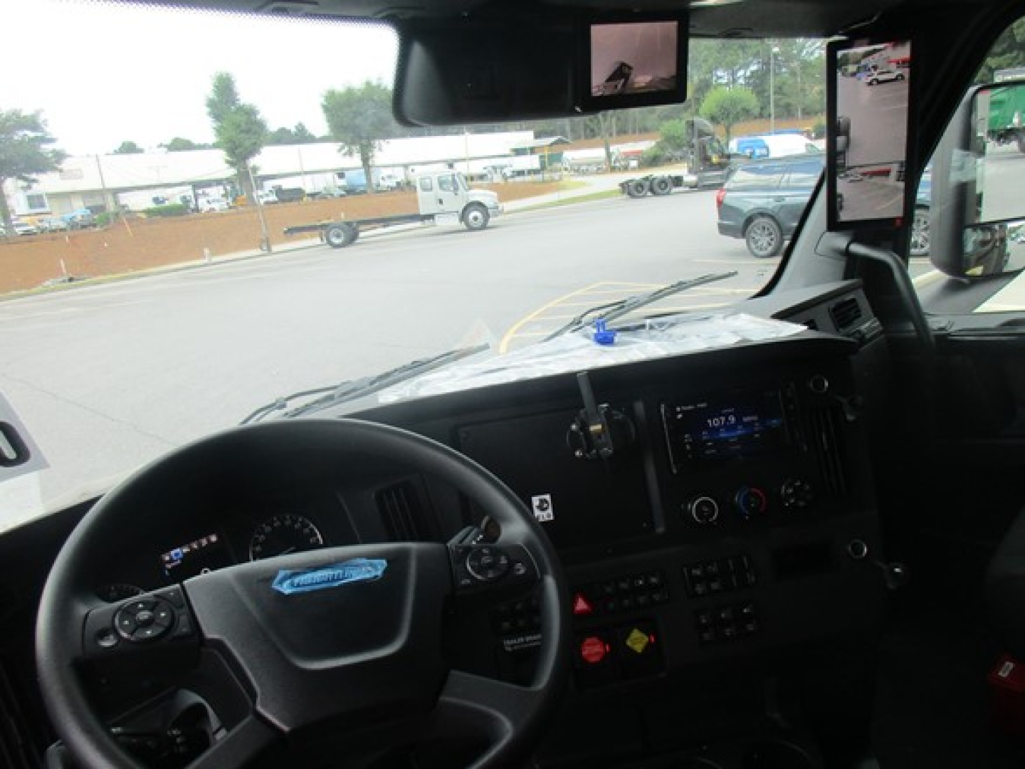 Freightliner Cascadia 126 truck cab interior showing steering wheel, dashboard, and windshield with road view.