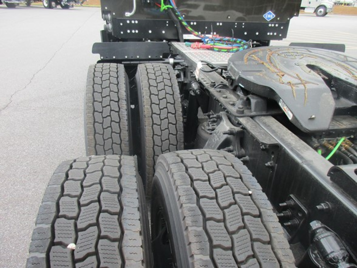 Truck drivetrain area showing dual rear axles with large tread tires and chassis frame components.