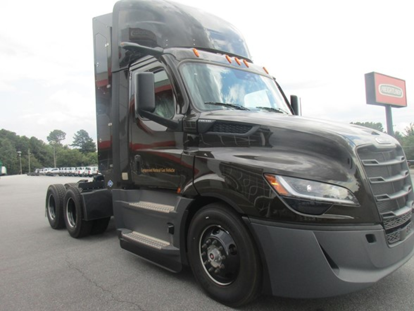 Freightliner Cascadia 126 tractor cab in a dealership lot with black paint and chrome accents; no visible labels readable beyond the truck silhouette and context text.
