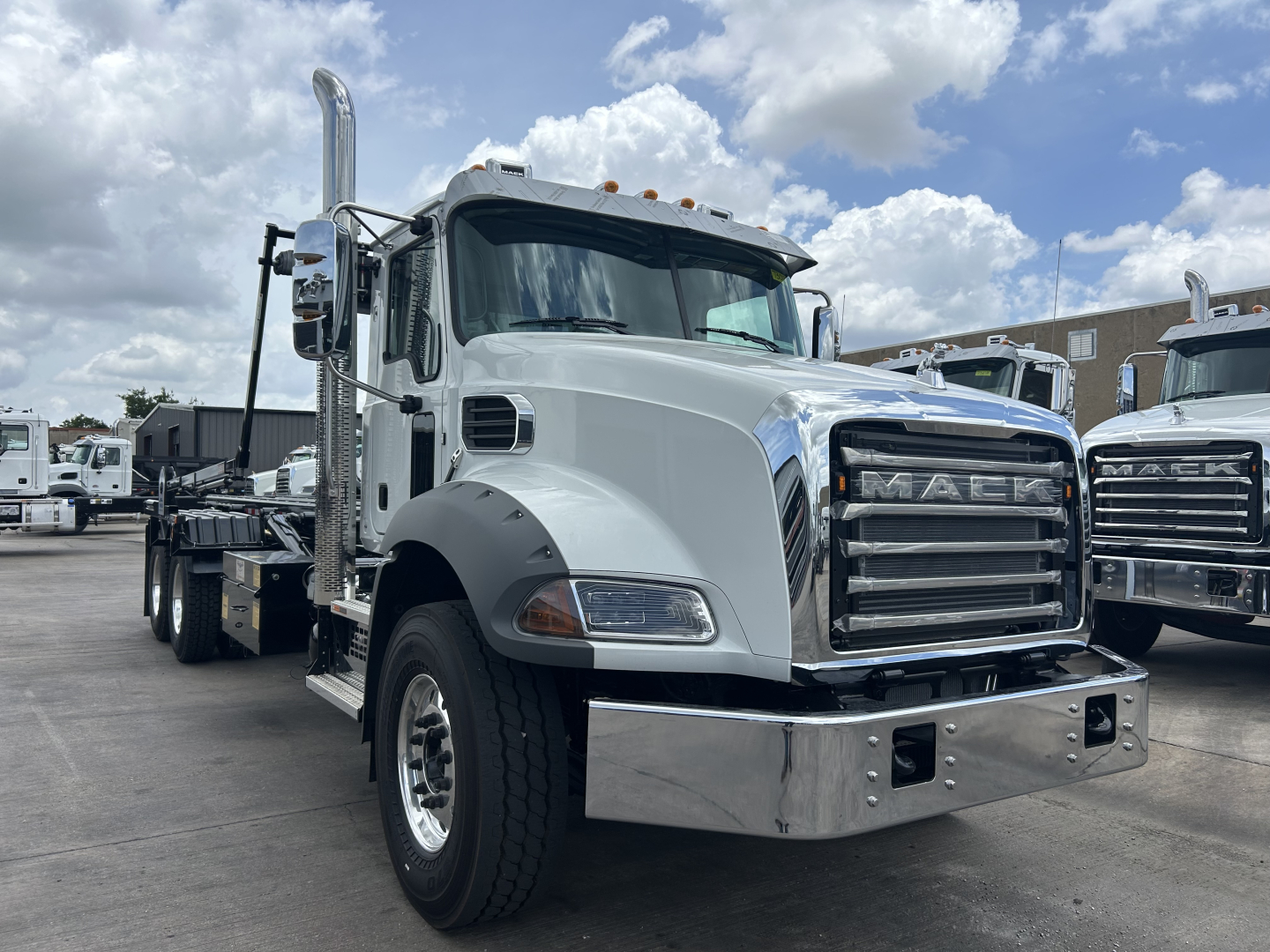 Mack GR64B roll-off truck cab and chassis showing chrome bumper, grille, vertical exhaust, and large mirrors.