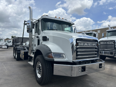 Mack GR64B roll-off truck cab and chassis showing chrome bumper, grille, vertical exhaust, and large mirrors.