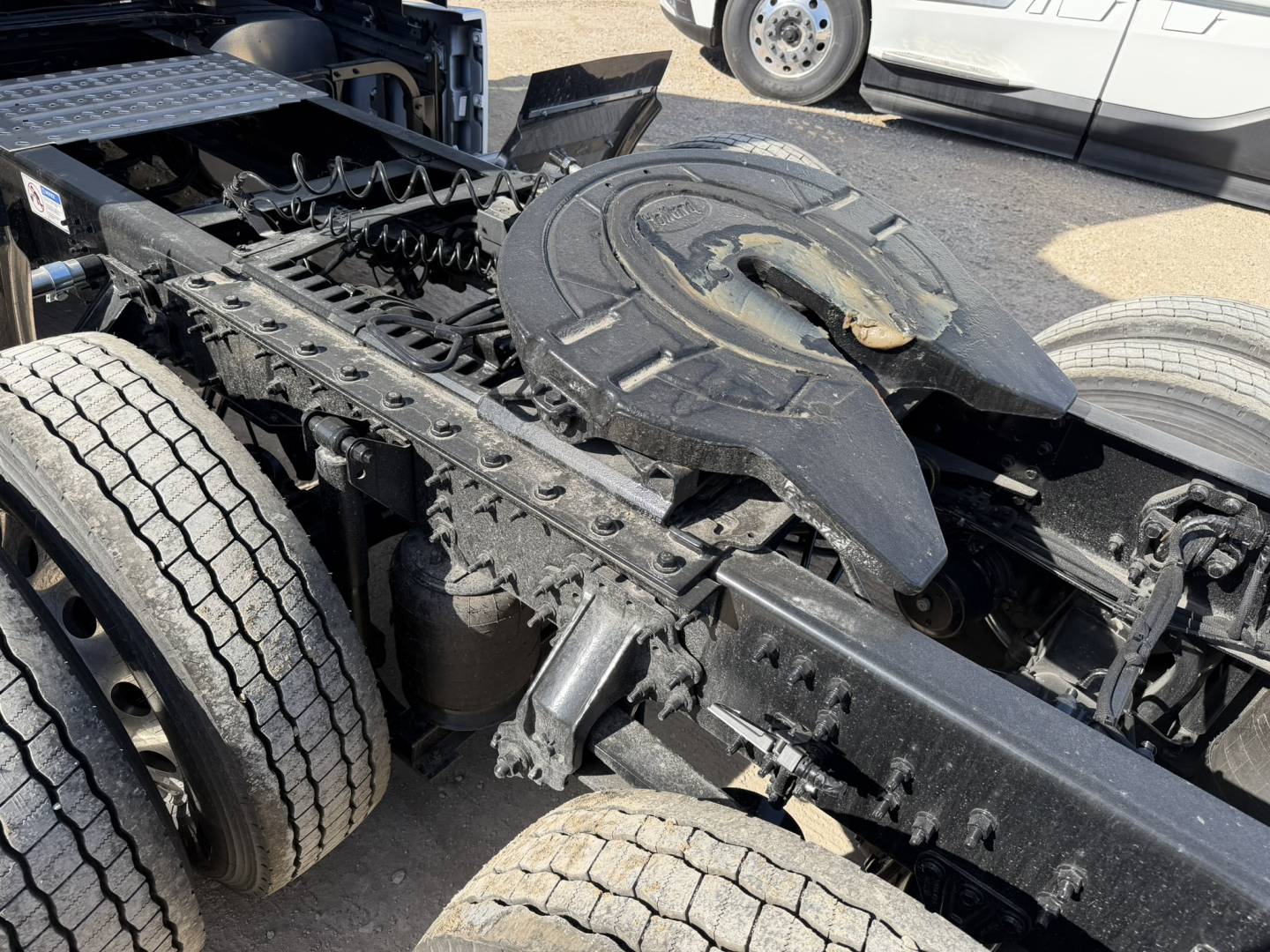 Chassis and fifth-wheel coupling area of a new Mack PR64T76H truck showing the hitch platform and rear axles.