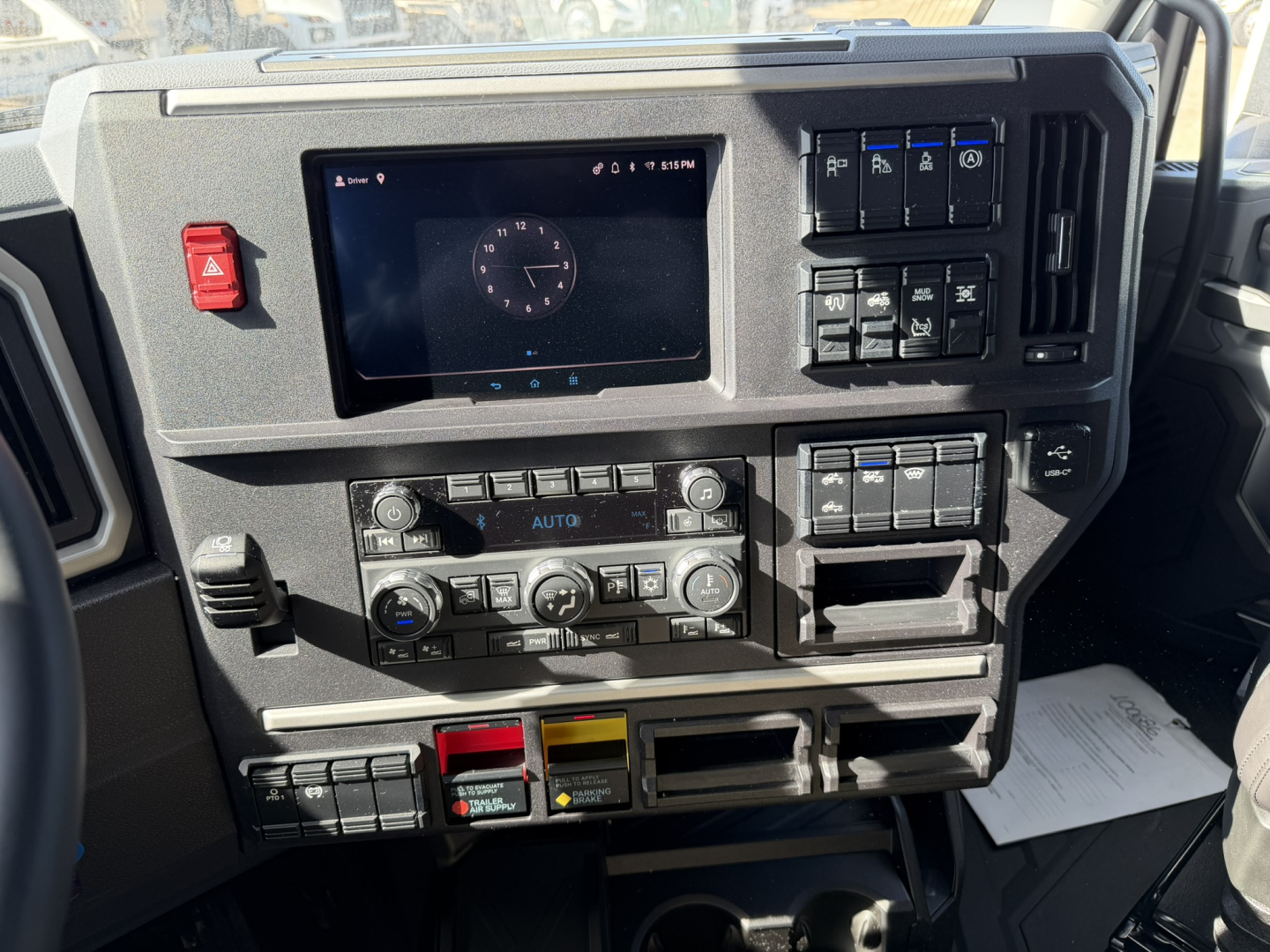 Mack truck dash with digital display, control panels, climate controls, and various switches. Visible text on buttons and panels.
