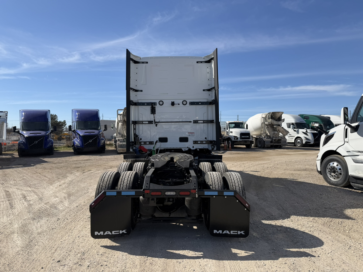 Mack PR64T76H tractor rear view showing fifth wheel and dual rear axles, with mud flaps labeled MACK and a clear sky.