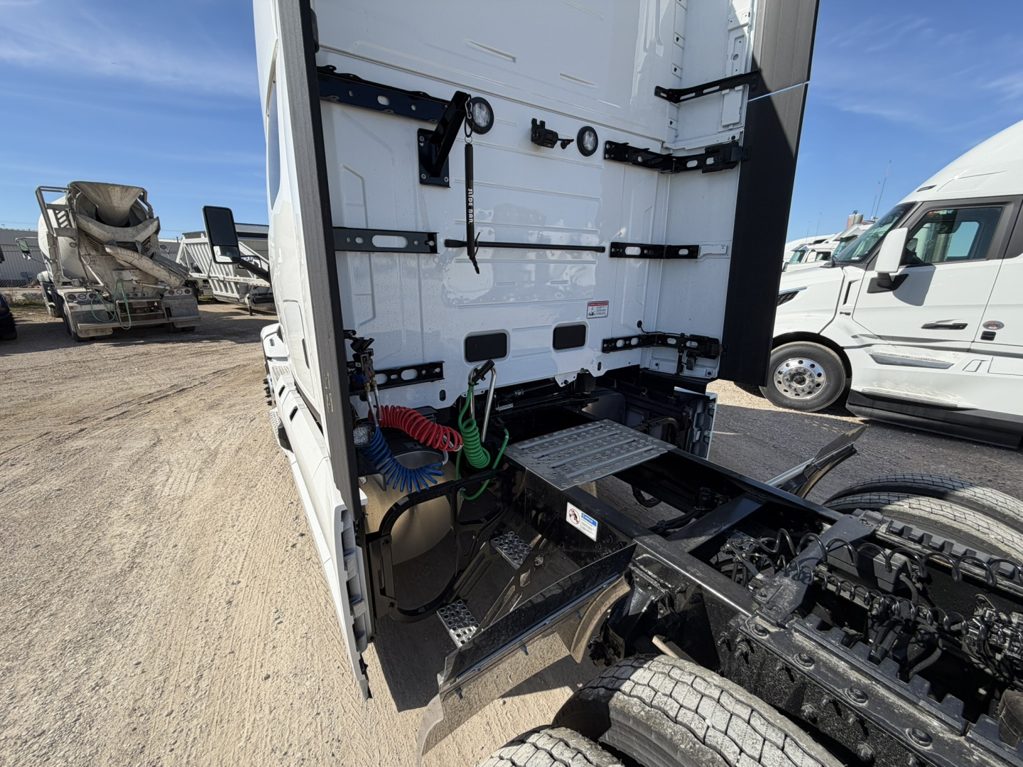 Tractor-trailer rear view showing cargo area and fifth wheel with hoses and tool storage compartments.