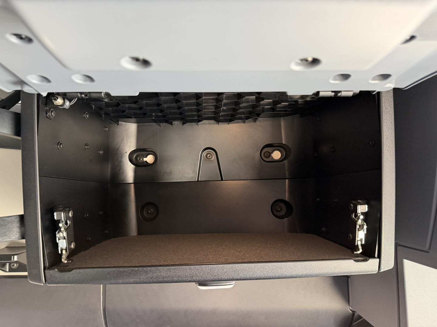 CABinet under dash area of a Mack PR64T76H truck showing open storage drawer with metal hinges and interior paneling