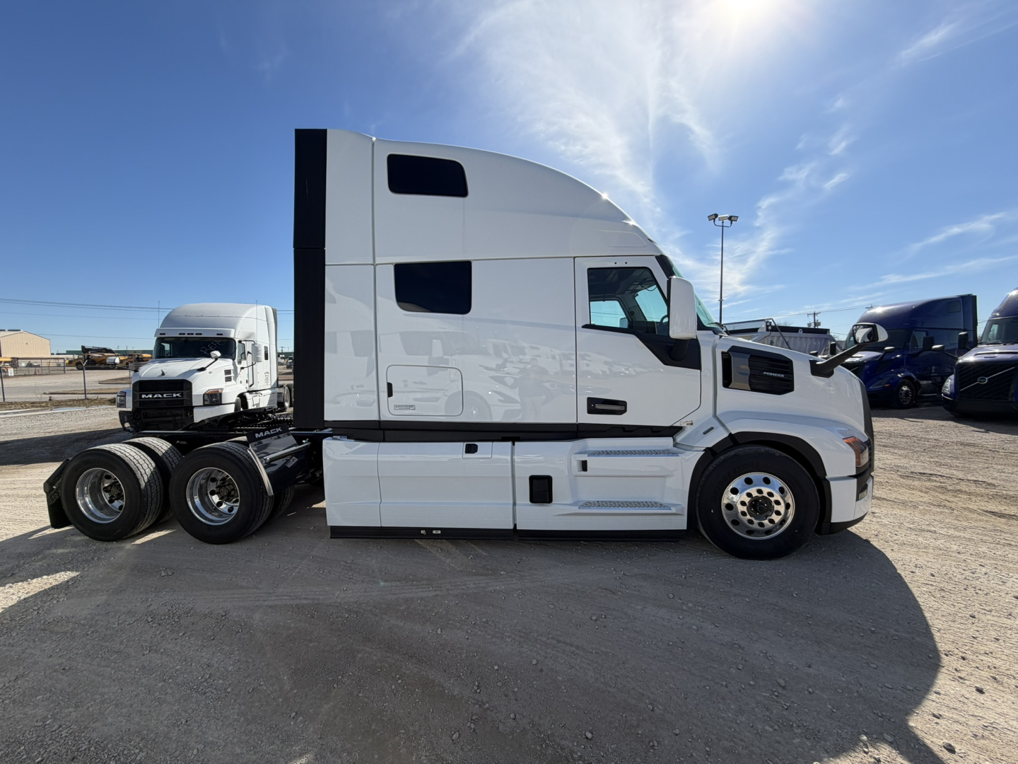 Truck cab side view showing 2026 Mack PR64T76H conventional sleeper with white paint, dual rear axles, and cab details.