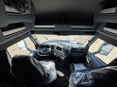 Cab interior of a new 2026 Mack PR64T76H truck showing steering wheel, dashboard, and driver seats covered in plastic.