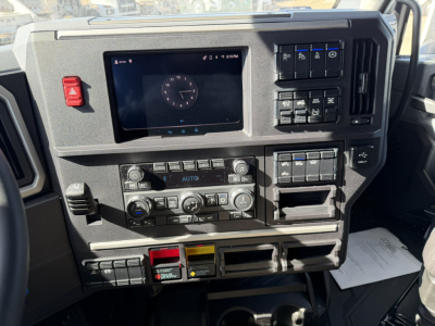 Mack truck dash with digital display, control panels, climate controls, and various switches. Visible text on buttons and panels.