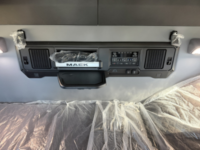Dashboard panel in Mack PR64T76H cab showing center console with control panel and storage pocket. Visible text includes 'MACK' on the center badge, and various control labels on the panel.