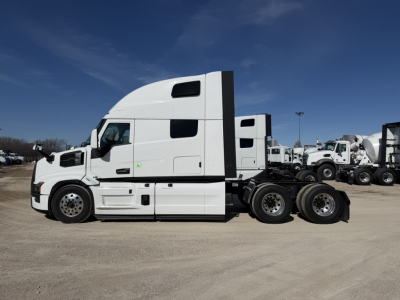 Truck cab side view showing Mack PR64T76H dual rear axles and sleeper unit with white exterior.