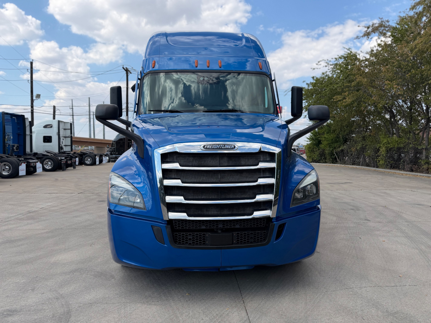 Front view of a blue Freightliner PT126064ST truck showing grille, headlights, and side mirrors.