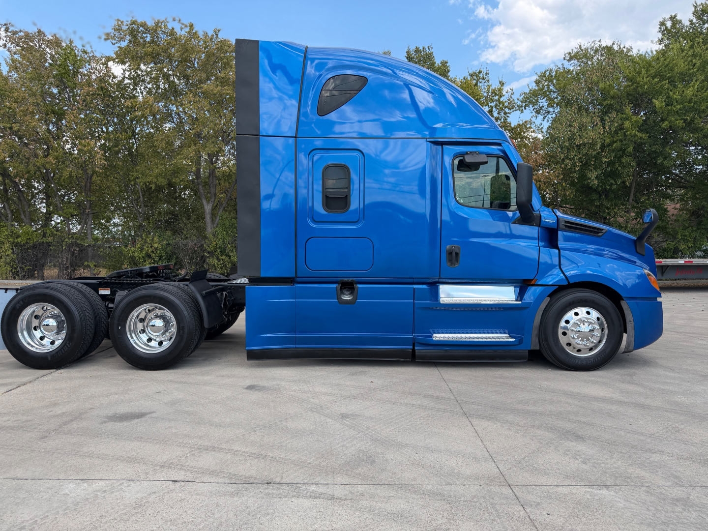 Freightliner PT126064ST tractor unit side profile showing blue cab and sleeper, chassis with dual rear axles, clean tires and chrome wheels.