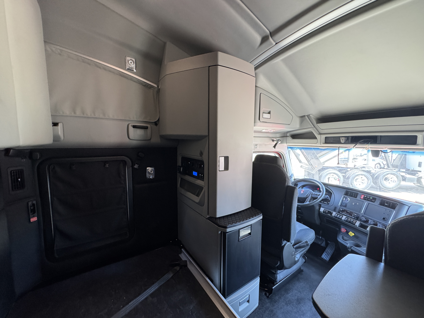Kenworth T680 cab interior showing driver seat and center console with storage cabinet and dashboard