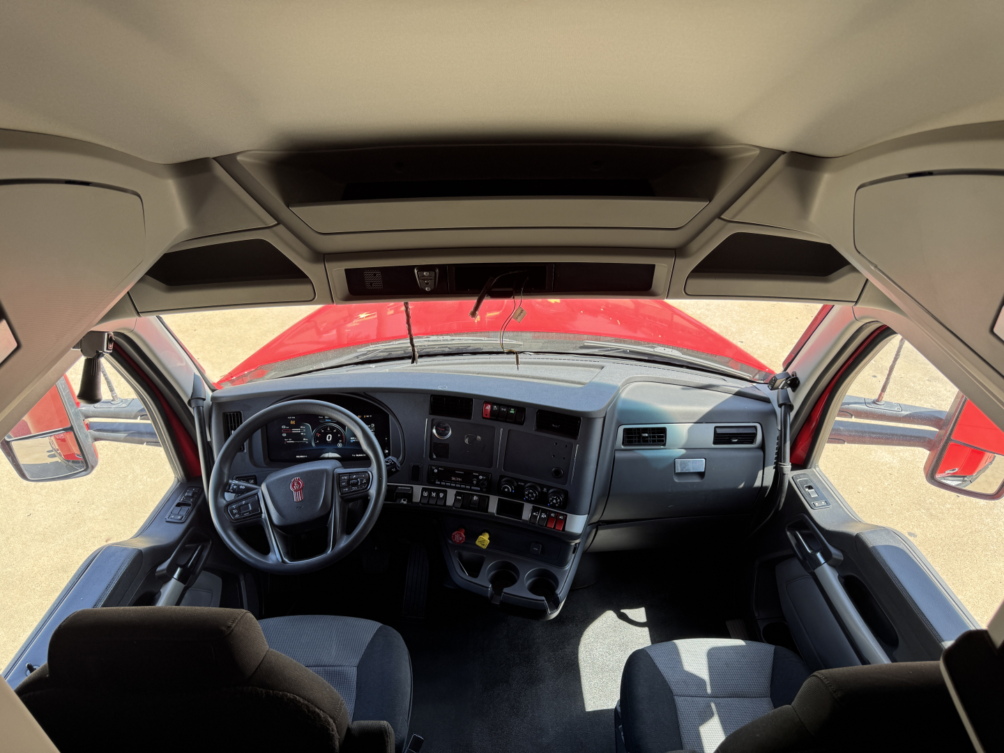 Kenworth T680 cab interior view from driver seat showing dashboard, steering wheel, and center console.