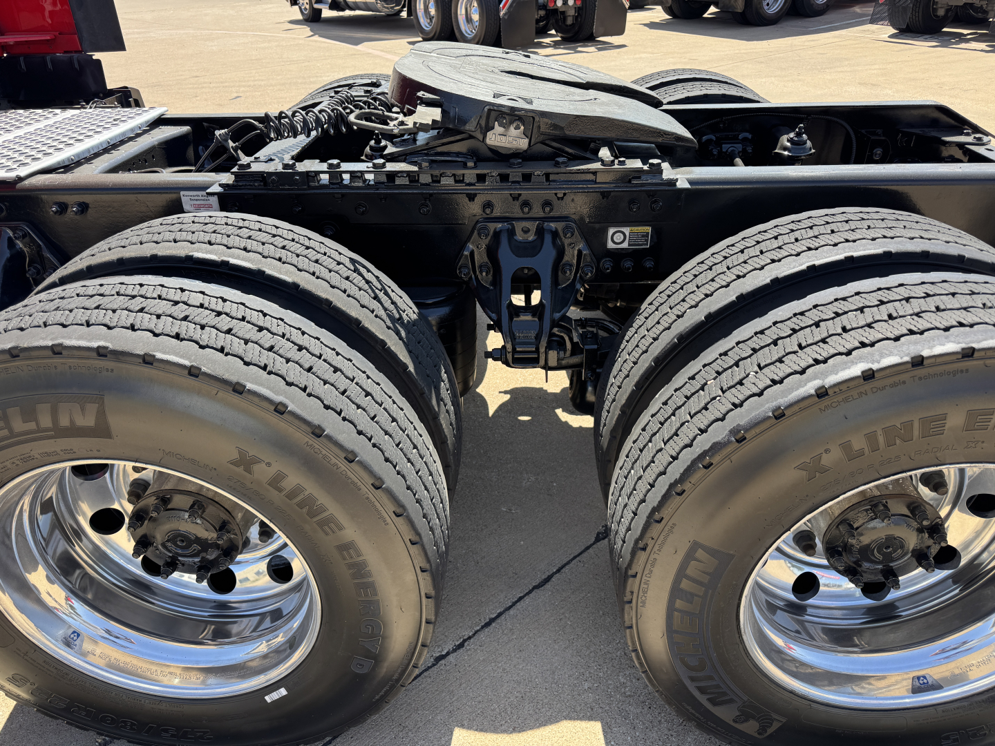 Kenworth T680 chassis showing dual rear axle wheels and suspension, with chrome wheels and X-Line tires, chassis frame and fifth wheel area visible.