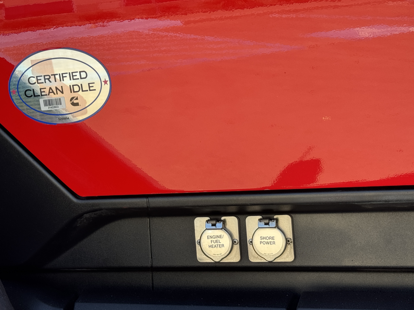 Kenworth T680 hood area with two labeled switches: ENGINE FUEL HEATER and SHORE POWER, and a Certified Clean Idle badge on red paint.