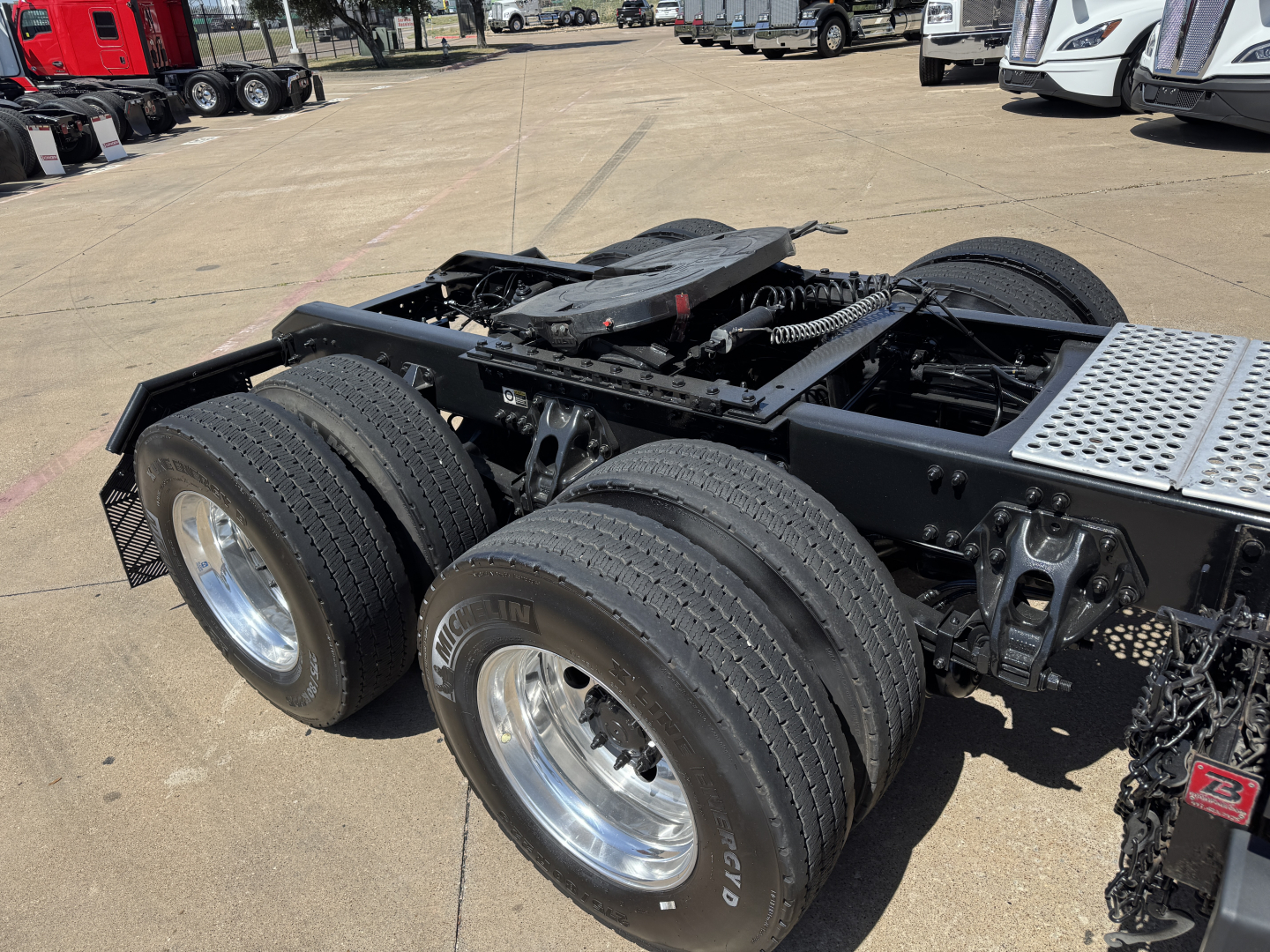 Kenworth T680 tractor rear chassis and dual rear axles with tires and fenders visible in a dealership lot.