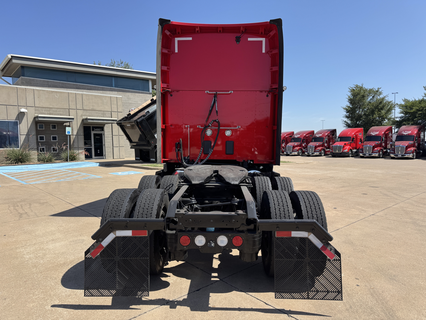 Kenworth T680 rear view showing fifth wheel area and dual rear axles with mud flaps and brake lights.