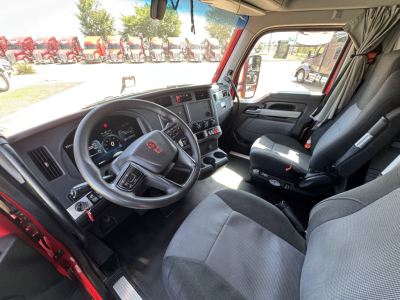 Kenworth T680 cab interior showing steering wheel, dashboard, driver seat, and passenger seat with center console.