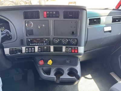 Kenworth T680 dashboard and center console view showing gauges, switches, climate controls, cup holders, and storage compartments.
