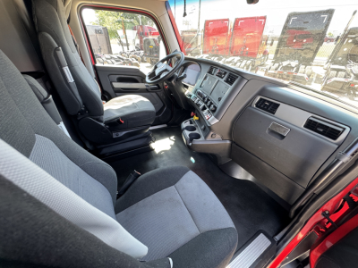 Interior of a 2023 Kenworth T680 cab showing driver seat, dashboard with steering wheel, and center console.