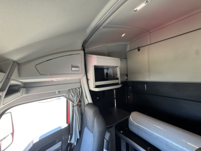 Kenworth T680 truck cab interior showing sleeper area and overhead storage cabinet.