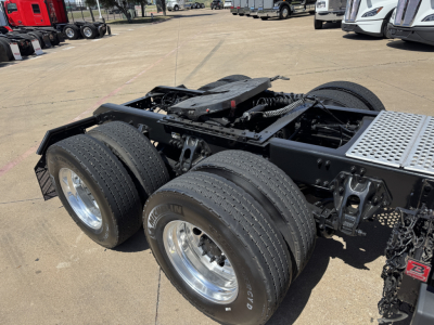 Kenworth T680 tractor rear chassis and dual rear axles with tires and fenders visible in a dealership lot.