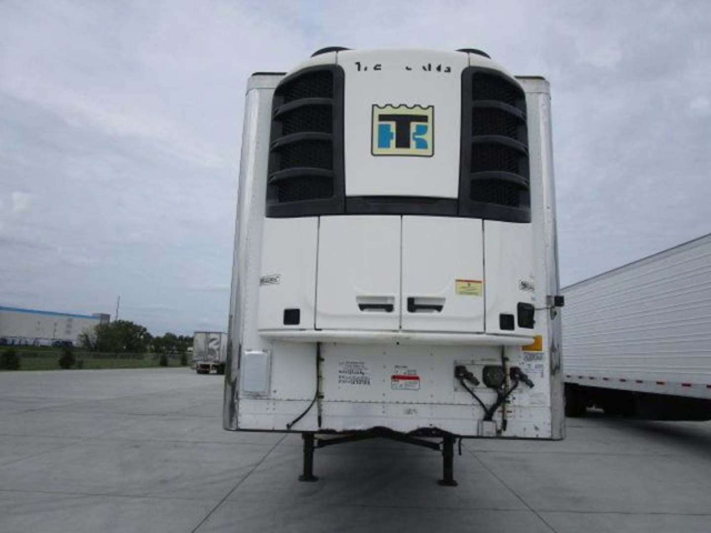 Refrigerated trailer rear showing HTS logo and cooling unit, bumper area, electrical connections, and support legs.