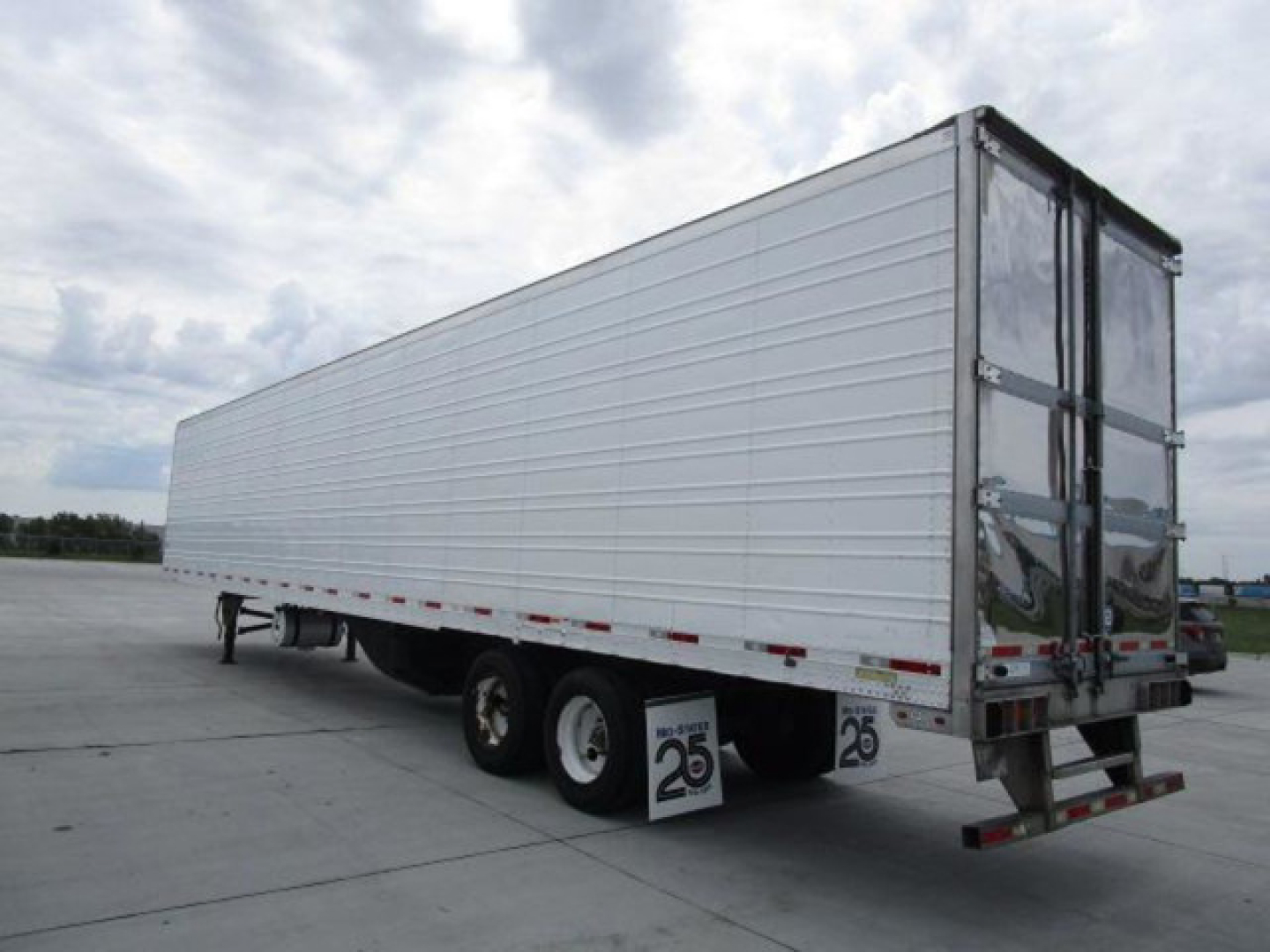 Utility refrigerated trailer with white side panels, dual rear doors, three-axle setup with two tires on each side visible; rear bumper and mudflaps display '25' placards.