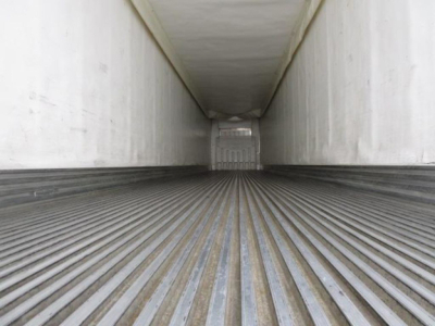 Trailer interior showing ribbed floor of a refrigerated trailer with loading door at far end.