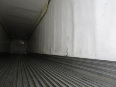 Trailer interior showing corrugated floor and white interior walls, empty cargo space with light at far end.