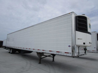 Utility reefer trailer showing Thermo King reefer unit at front with raised legs and reflective aluminum walls.