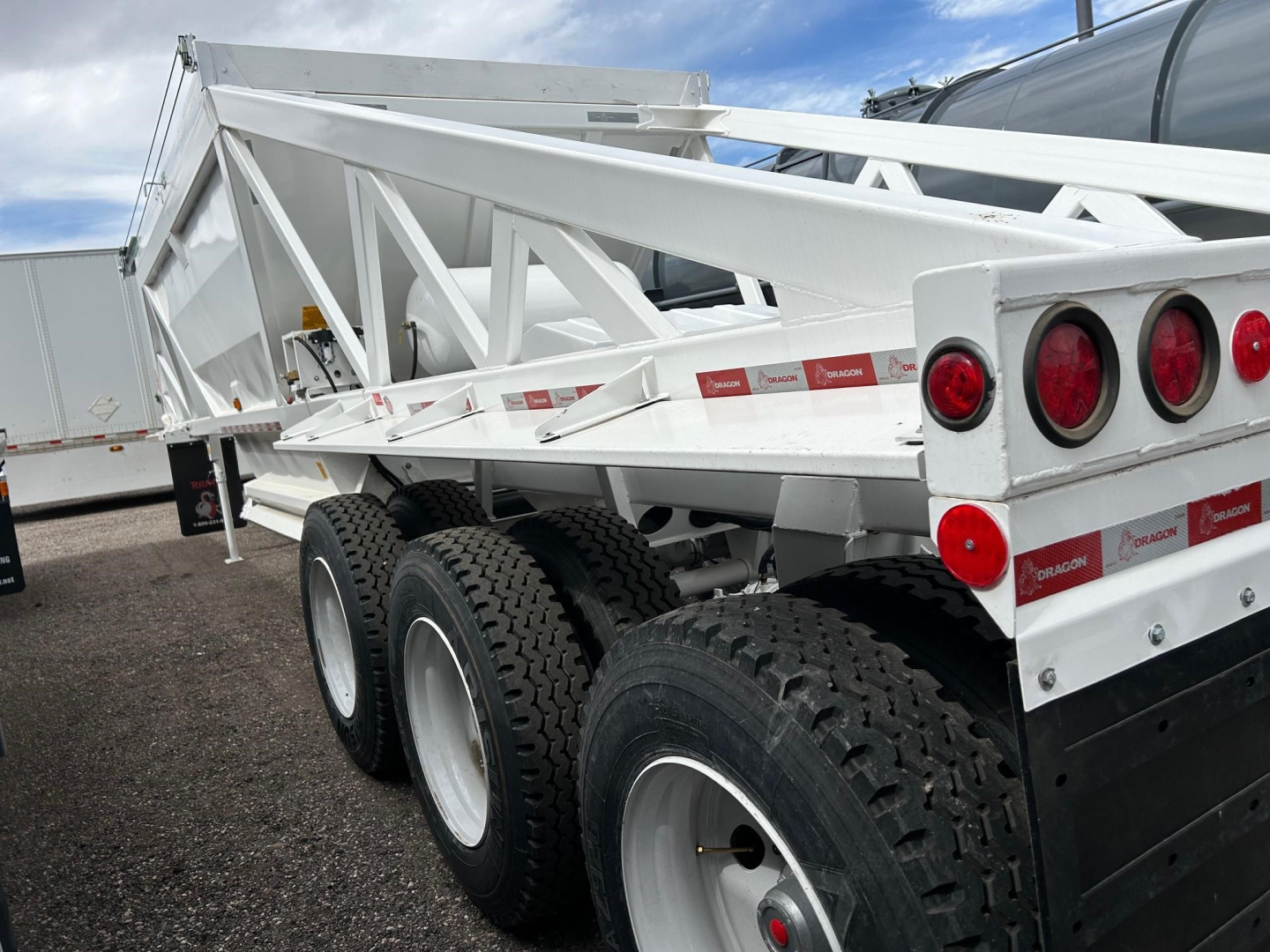 Ranco Versa dump trailer showing side rails and dual rear wheels with white frame and red reflectors.