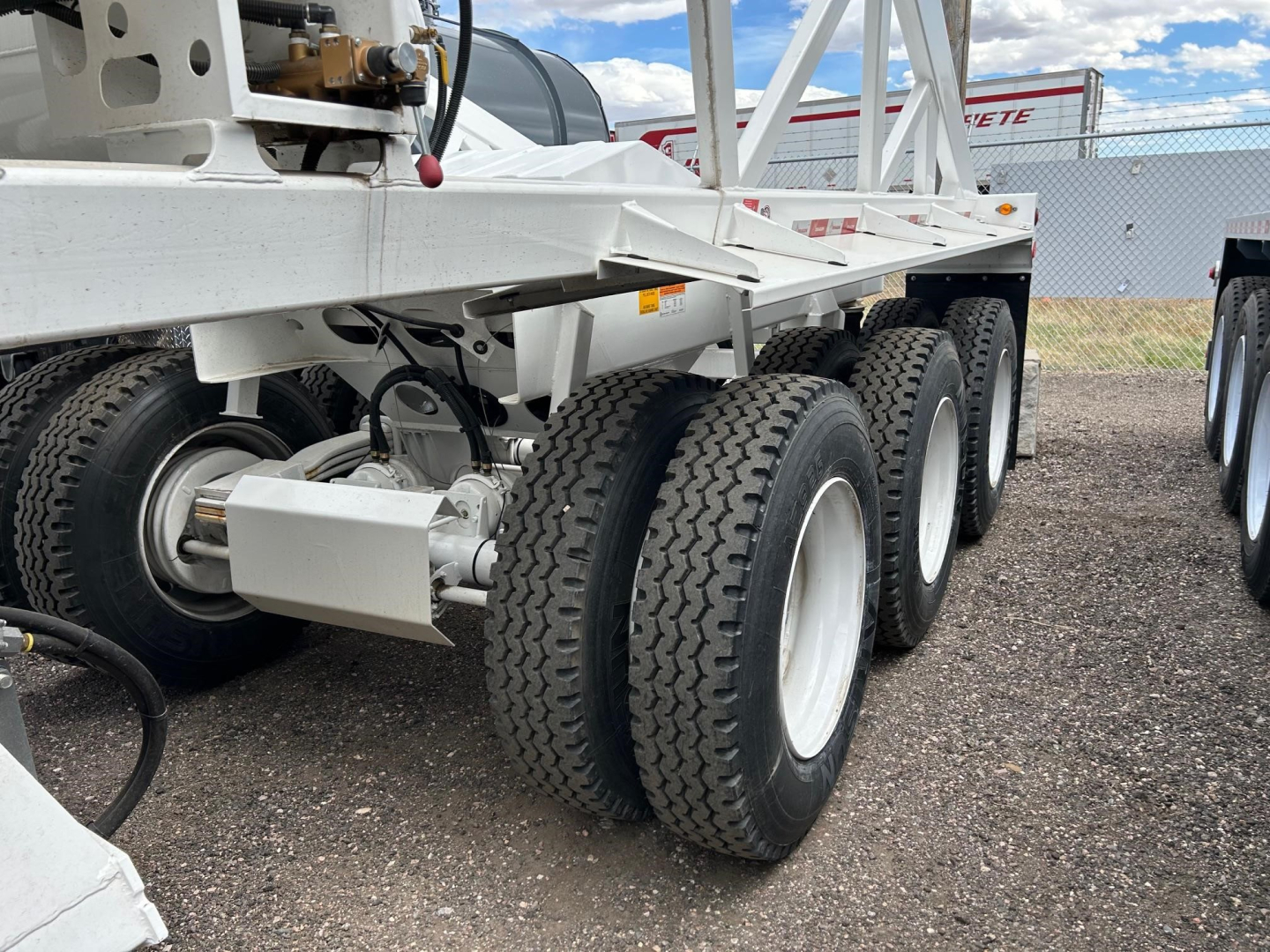 Versatile dump trailer undercarriage showing multiple axles and heavy-duty tires with white wheels and frame components.