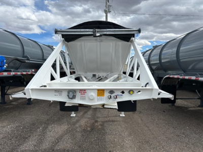 Dump trailer hopper with white frame and black tarp, rear view showing spread axles and control panel labels.