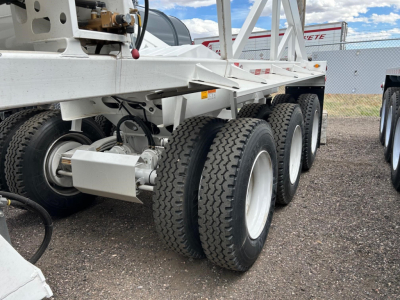 Versatile dump trailer undercarriage showing multiple axles and heavy-duty tires with white wheels and frame components.