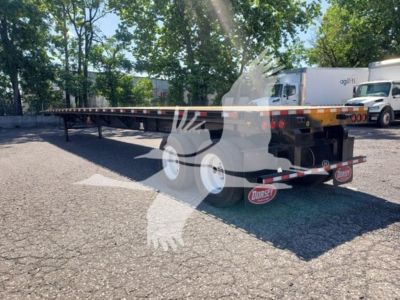 Flatbed trailer showing long black deck with yellow railing, rear wheels, and Dorsey branding on mud flaps.