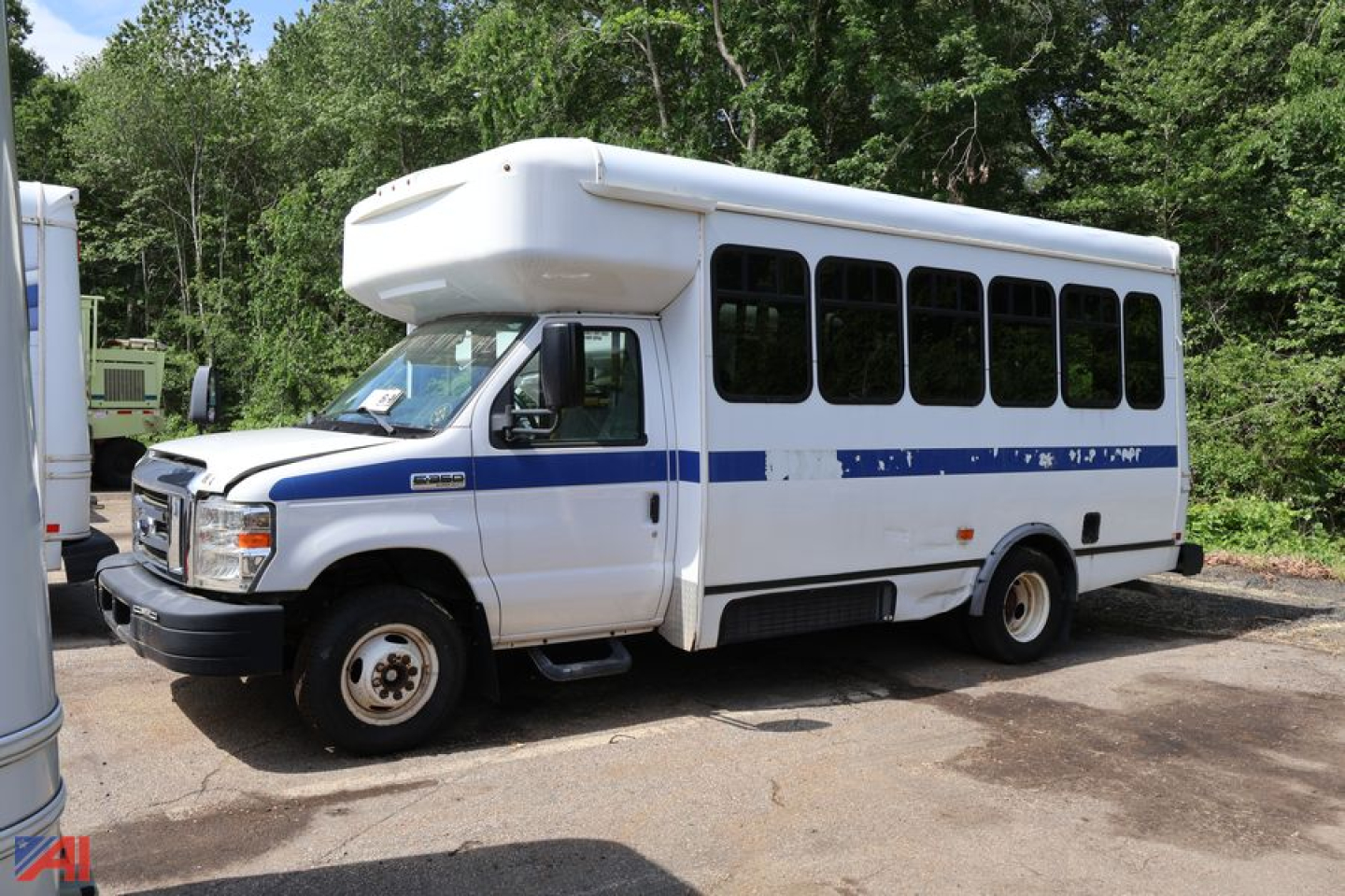 Ford E-350 shuttle bus with wheelchair lift roof, side windows, blue stripe, front grille, used in-service vehicle.