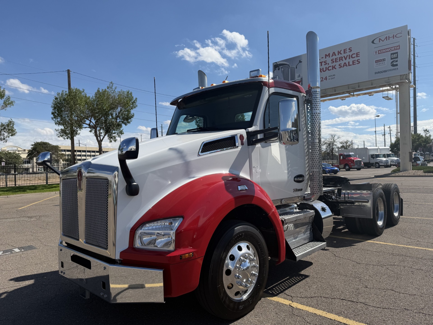 Kenworth T880 conventional daycab tractor in white and red front quarter view, showing chrome bumper, dual exhaust stacks, and side steps.