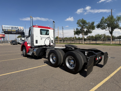 Kenworth T880 conventional daycab tractor in a parking lot showing rear chassis and dual rear axles.