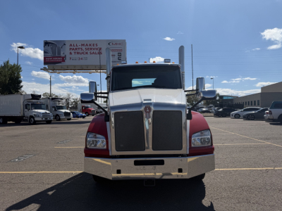 Kenworth T880 front view showing large grille and bumper, chrome mirrors, and red fenders in a dealership lot.