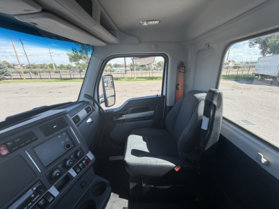 Interior of a Kenworth T880 cab showing driver and passenger seats, dashboard with control panel, steering column, side window, and door.