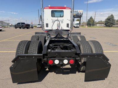 Kenworth T880 rear view showing fifth-wheel area and dual rear axles with mud flaps and toolbox covers in a parking lot.