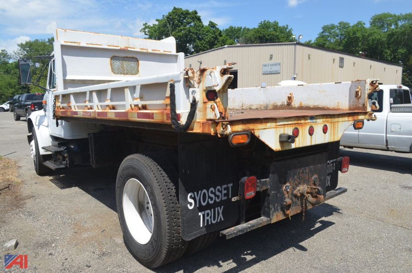 Dump truck bed and rear of a 1996 International 4700 in-service with rusted metal hopper and black rear bumper area.